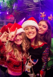 two girls a=in santa hats at the ugly christmas sweater bar crawl